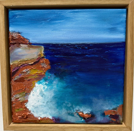 Framed painting of a coastal scene with cliffs and ocean.