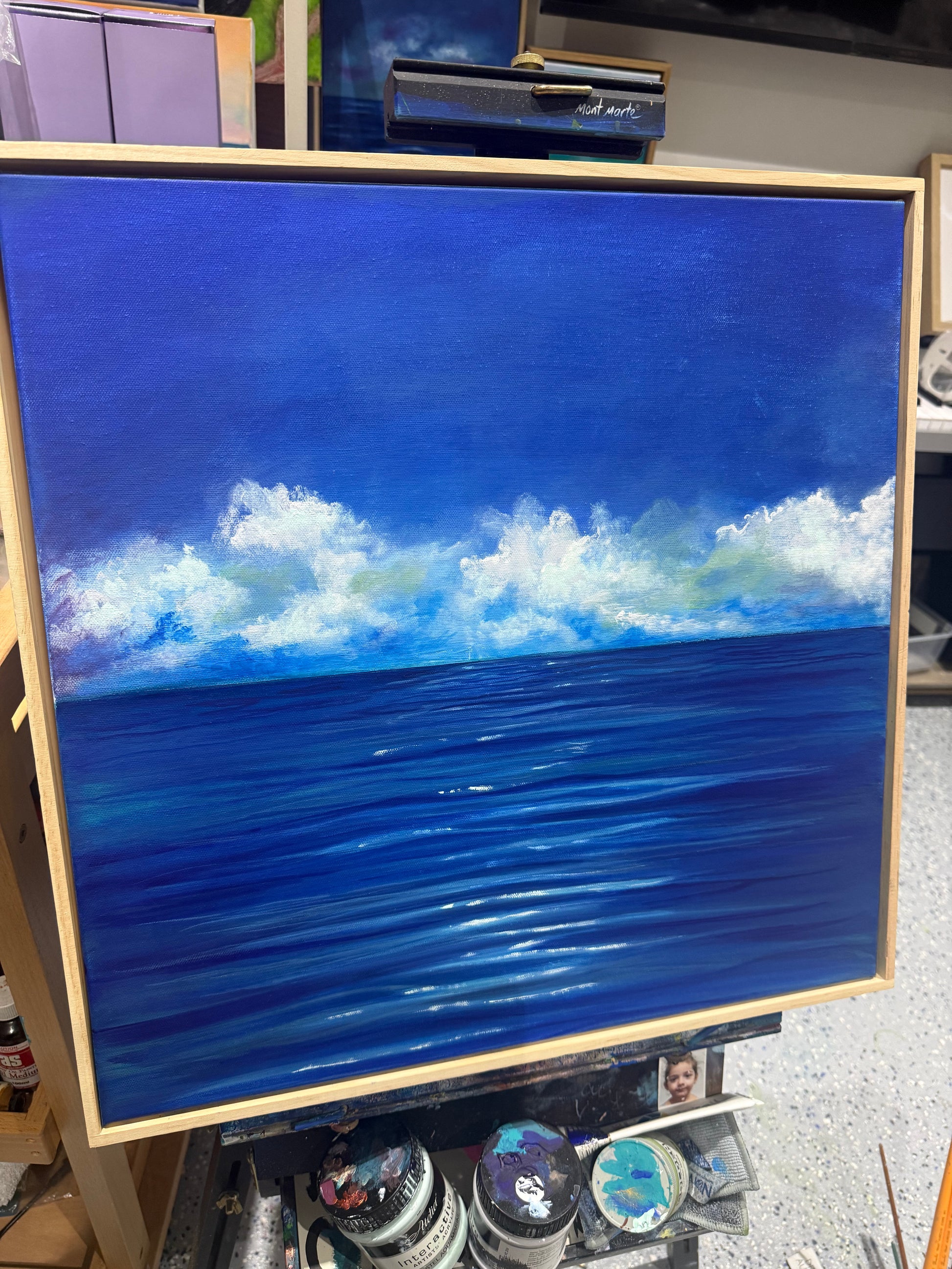 The Weight of Blue by Dallal Naser. Blue Ocean and White Clouds on easel